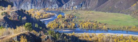 Autumn landscape over a mountain river. Forest, meadow and blue waters of the river.の写真素材
