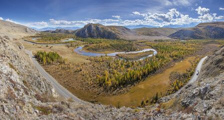 A river flows meandering along a picturesque valley. Sunny autumn day. Panoramic view.の写真素材