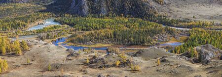 Autumn view. The river flows in a mountain valley, overgrown with forest. Pano, natural background.