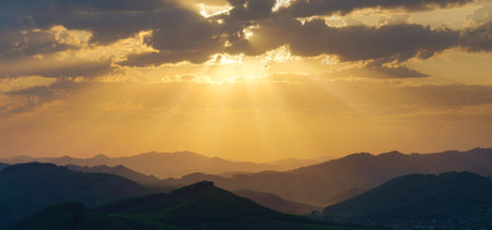 Picturesque sunrise in the mountains, sun rays through the cloudsの写真素材
