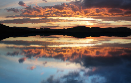 Beautiful reflection of a bright sunset in the lake. Rest in the wild.の写真素材