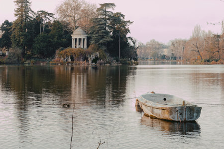 Stunning rotunda and artificial grotto at ile de Reuilly by Lake Daumesnil at sunset, with a weathered boat floating serenelyの写真素材