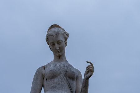 Sculpture of a classical figure with graceful pose against a soft blue sky backdrop in an outdoor settingの写真素材