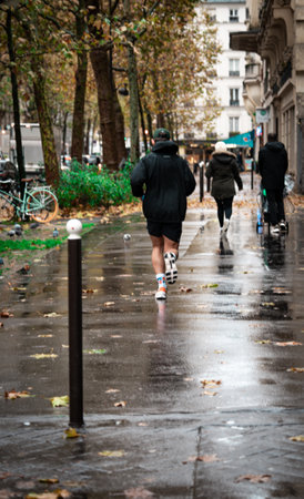 People jogging on a rainy street in an urban park during autumnの写真素材