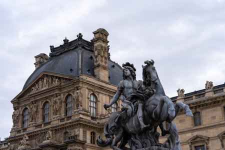 Equestrian statue in front of an ornate building in Paris on a cloudy day with historical...