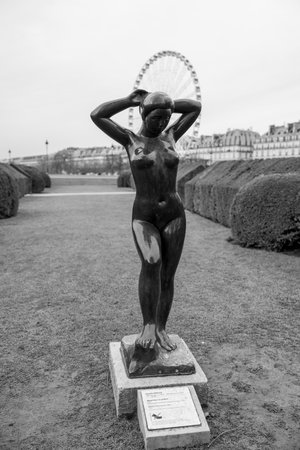 Sculpture of a nude woman with raised arms in a garden, surrounded by bushesの写真素材