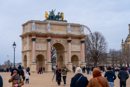 Historic monument attracts visitors in a bustling Paris square during a cloudy dayの写真素材