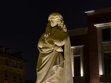 Statue of a historical figure illuminated at night in a vibrant urban settingの写真素材