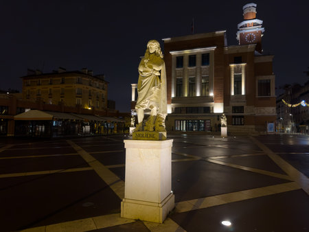 Nighttime view of historic square featuring statue and illuminated architecture in a charming town sceneの写真素材