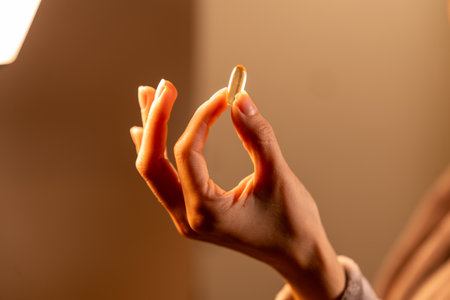 Close-up of a hand holding an omega 3 supplement capsule in soft natural light with a warm backgroundの写真素材