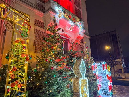Festive holiday decorations adorn a building with colorful lights and Christmas trees at night in a cityの写真素材