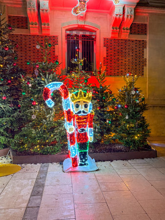 Colorful nutcracker decoration stands among illuminated Christmas trees at a festive outdoor display in Decemberの写真素材