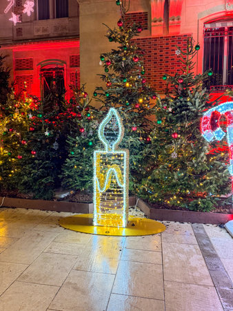 Holiday decorations illuminate a festive street with Christmas trees and a glowing candleの写真素材