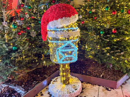 Brightly decorated mailbox with Christmas lights and a Santa hat surrounded by festive trees at a holiday displayの写真素材