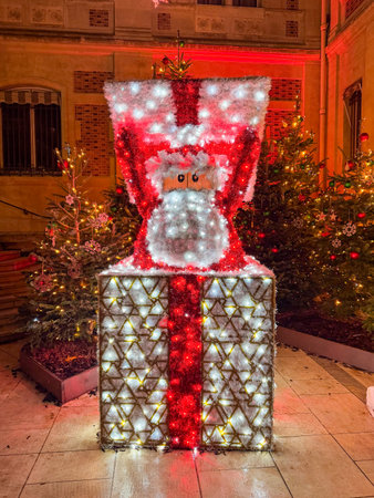 Festive decorations featuring a large illuminated Santa figure in a gift box during Christmas celebration in a town squareの写真素材