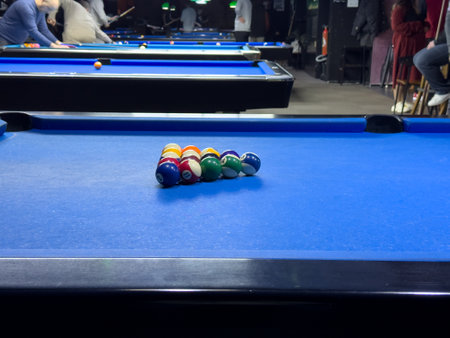 Pool table set up with balls ready for a game in a lively bar settingの写真素材
