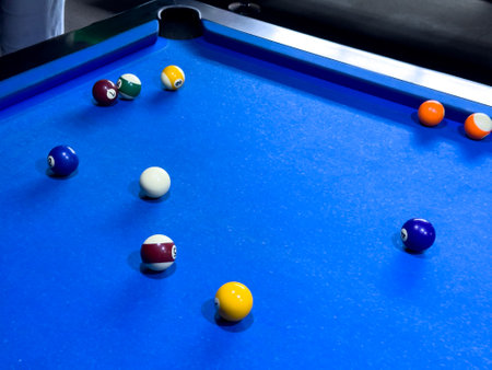 Brightly colored billiard balls on a blue pool table during a game
