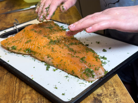 Preparing fresh salmon with herbs in a cozy kitchen settingの写真素材