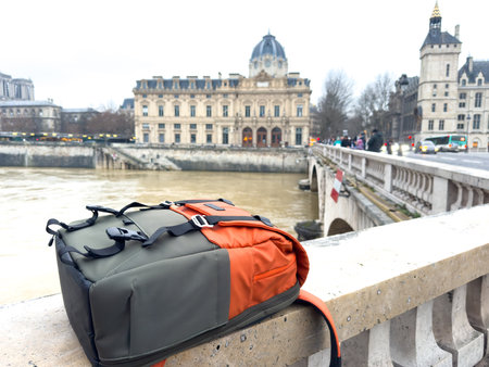 Backpack resting on a bridge overlooking a historic building in Parisの写真素材