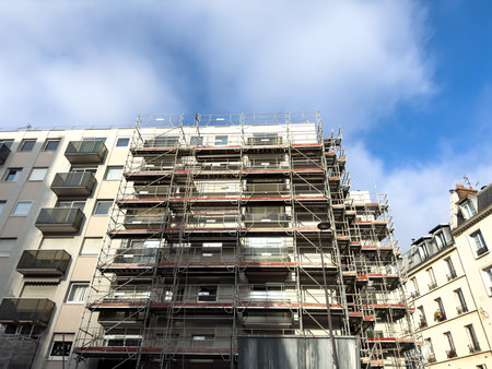 Building renovation with scaffolding under blue sky and cloudsの写真素材