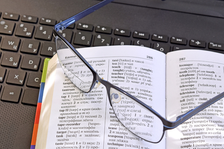 dictionary, glasses and laptop keyboardの写真素材