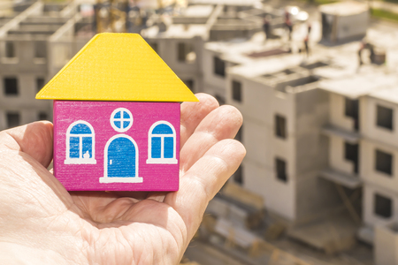 Wood house in hand on a background of constructionの写真素材