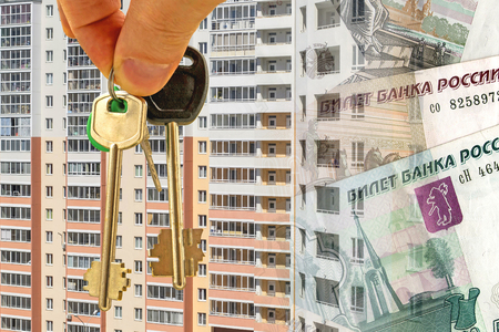 The keys to the apartment on a background of money and houses. The concept of changes in property pricesの写真素材