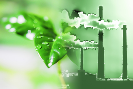 Industrial factory chimneys on background of green plants. The concept of relevance for the protection of nature.の写真素材