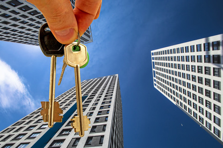 The keys to the apartment in the background of the facade of the house. The concept of sales in the real estate market.の写真素材
