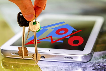 The keys to the apartment in the background of the cell phone. The concept of online property sales.の写真素材