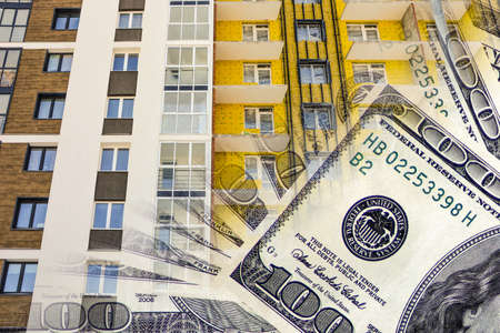 The facade of a residential high-rise house on a background of money. The concept of selling in the real estate market.の写真素材