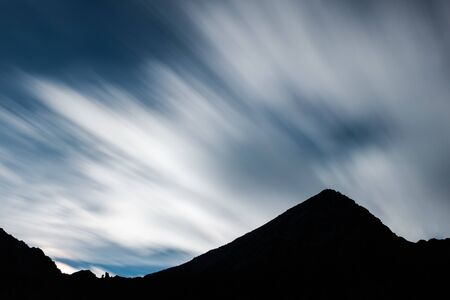 Silhouette of Mount Emilius with fast clouds passing in the skyの写真素材