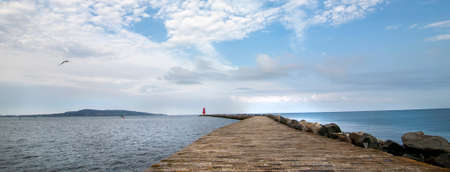 A panoramic shot of a pier with a red lighthouse in the backgroundの写真素材