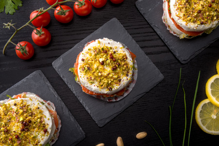 Pie with soft cheese and smoked salmon filling of chopped pistachios, served on a stone on the table trayの写真素材