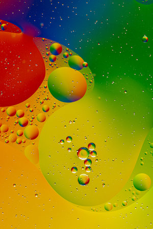 bright oily drops in water with colorful background, closeup of colorful bubbles