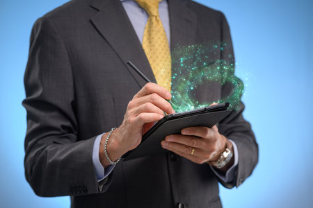 Businessman holding a tablet computer with a glowing green network hologramの写真素材