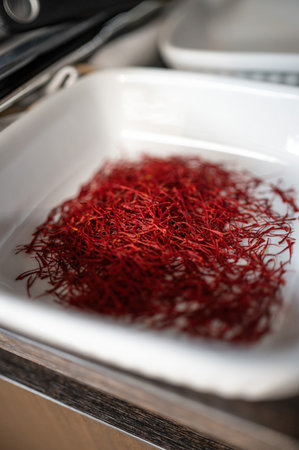 Saffron threads in a white ceramic bowl on a wooden tableの写真素材