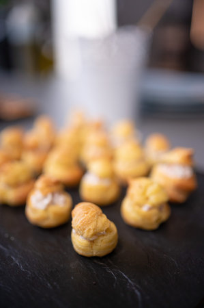 Homemade profiteroles on a black slate plate, selective focus