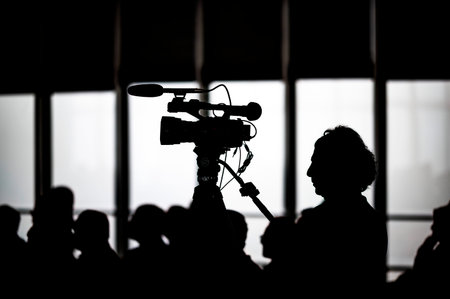 Silhouette of a cameraman in front of a large audience