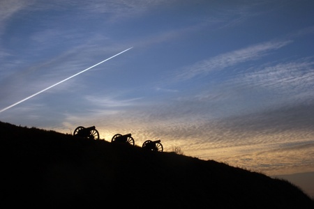silhouettes of three big guns in the evening skyの写真素材
