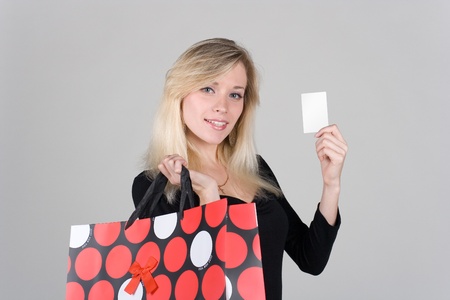 Young girl with bag confidence shows a blank plastic cardの写真素材