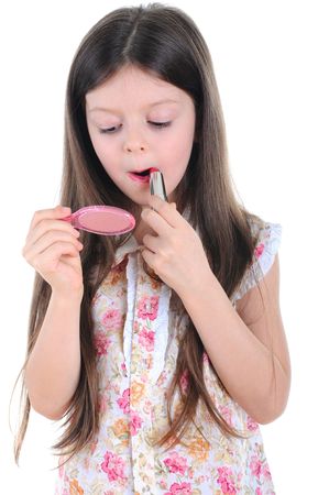 The little girl paints lips with lipstick before a mirror. Isolated on white backgroundの写真素材
