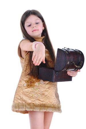 The little girl tries on a bracelet from a chest.  Isolated on white backgroundの写真素材