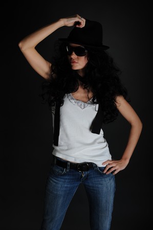 Portrait of a girl in a white T-shirt, hat and sunglasses on a black backgroundの写真素材