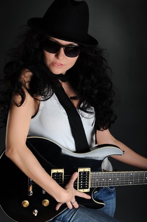 Portrait of a girl in a hat with a black guitar in his handsの写真素材