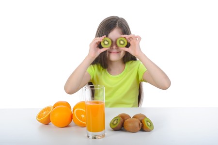 Girl shows kiwi slices sitting at the table. Isolated on white backgroundの写真素材