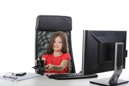 little girl with a cup of coffee at a table in front of a computer. Isolated on white backgroundの写真素材