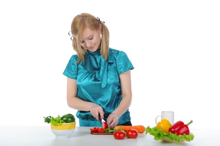 Young smiling woman prepares breakfast at the kitchen table. Isolated on white background.の写真素材