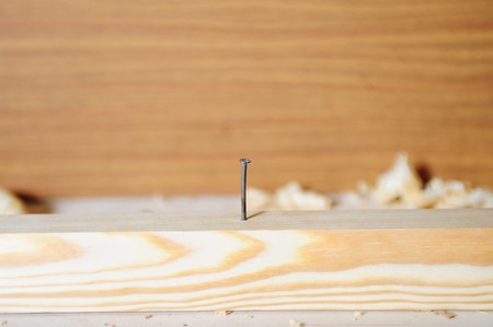 iron nail hammered into a wooden blockの写真素材