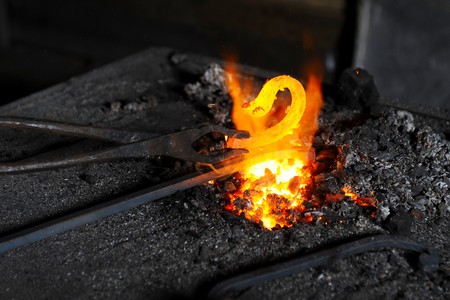 blacksmith heats a decorative piece in the forgeの写真素材